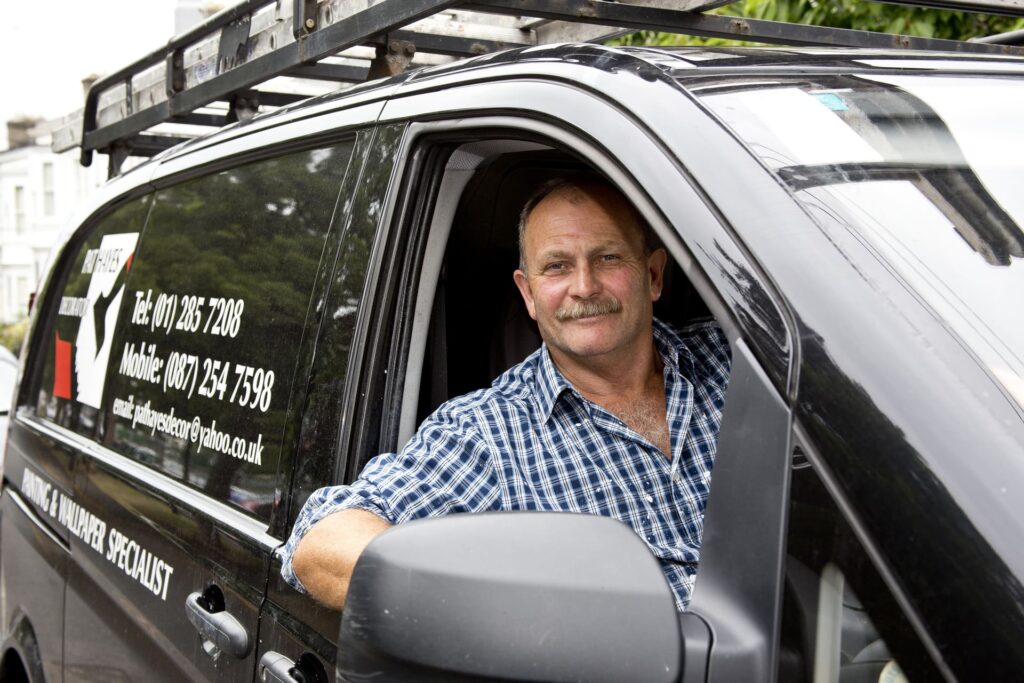 A smiling painter sitting in his van.